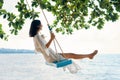 Carefree happy woman on swing on beautiful paradises beach