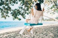 Carefree happy woman on swing on beautiful paradises beach