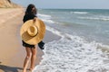 Carefree happy woman with windy hair holding hat and having fun on sandy beach at sea. Summer vacation. Stylish fit young female Royalty Free Stock Photo