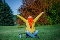 Carefree hipster woman with raised hands sitting on green lawn enjoying good weather. Outdoor coffee break. Happy lifestyle Royalty Free Stock Photo