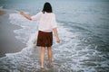 Carefree woman walking barefoot in cold sea waves on sandy beach, enjoying calm evening. Mindfulness Royalty Free Stock Photo