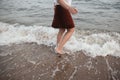 Carefree hipster woman walking barefoot in sea waves on beach. Feet in water foam, summer vacation Royalty Free Stock Photo