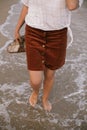 Carefree hipster woman walking barefoot in sea waves on beach with flip flops in hand. Relaxing Royalty Free Stock Photo