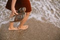 Carefree hipster woman walking barefoot in sea waves on beach, with flip flops in hand. Mindfulness Royalty Free Stock Photo