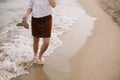 Carefree hipster woman walking barefoot in sea waves on beach, with flip flops in hand. Mindfulness Royalty Free Stock Photo