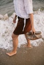 Carefree hipster woman walking barefoot in sea waves on beach, with flip flops in hand. Mindfulness Royalty Free Stock Photo