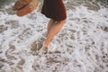 Carefree hipster woman walking barefoot in sea waves on beach, with flip flops in hand. Mindfulness Royalty Free Stock Photo