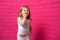 Carefree joyful little girl laughing out loud giggling covering her mouth with her hand on pink background Royalty Free Stock Photo