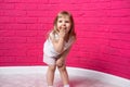 Carefree joyful little girl laughing out loud giggling covering her mouth with her hand on pink background Royalty Free Stock Photo