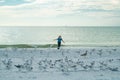 Carefree kid running, chasing birds. Kid boy chasing birds near summer sea beach. Happy child playing with seagull birds Royalty Free Stock Photo