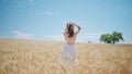 Carefree lady stepping golden crops back view. Happy young woman looking camera