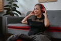 Carefree middle aged woman wearing wireless headphones, listening to music, relaxing on sofa at home Royalty Free Stock Photo