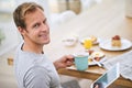 Carefree morning at home. Portrait of a handsome man using his tablet while having breakfast at home.