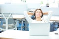 Carefree pretty woman sitting and relaxing on workplace in office