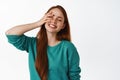 Carefree redhead woman laughing, smiling white teeth, close eyes and touch face gently, feeling free and happy, standing