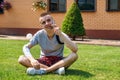 Man with amputated arm and prosthesis talking on the phone sitting on the lawn