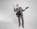 Carefree senior businessman singing over megaphone and playing electric guitar on white background Royalty Free Stock Photo