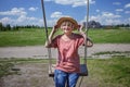 Carefree senior woman in straw hat swinging on a wooden swing, age beauty, baby boomer generation Royalty Free Stock Photo