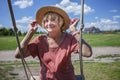 Carefree senior woman in straw hat swinging on a wooden swing, age beauty, baby boomer generation Royalty Free Stock Photo