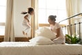 Carefree small daughter jump on bed while vietnamese mother laughing Royalty Free Stock Photo