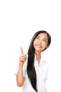 Carefree smiling Asian woman pointing finger up and looking up Royalty Free Stock Photo