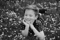 Carefree smiling boy lying on flower field. Cute kid child enjoying on lawn and dreaming.