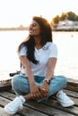 Carefree smiling Indian woman sitting on the wooden pier