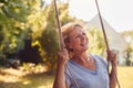 Carefree Smiling Retired Woman Having Fun On Garden Swing Royalty Free Stock Photo