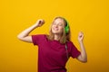 Carefree smiling young woman listens music in headphones holds mobile phone chooses song from playlist dressed in casual t-shirt Royalty Free Stock Photo