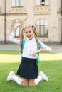 Carefree student. Smiling pupil sit on grass. Have fun. Happy kid relaxing outdoors. Cheerful schoolgirl. Schoolgirl