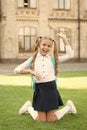 Carefree student. Smiling pupil sit on grass. Have fun. Happy kid relaxing outdoors. Cheerful schoolgirl. Schoolgirl
