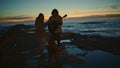 Carefree teenagers silhouettes relaxing morning seaside. Couple with cute dog Royalty Free Stock Photo