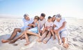 Carefree three generation family sitting together in the sand while spending time together at the beach. Loving parents Royalty Free Stock Photo
