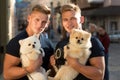 Carefree time together. Twins men hold pedigree dogs. Muscular men with dog pets. Happy twins with muscular look. Spitz