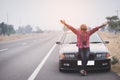 Carefree tourist african man stands on the highway road with arms outstretched in freedom pose with black car