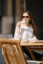 Carefree woman sitting on the terrace of the cafe and drinking cappuccino Royalty Free Stock Photo