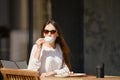 Carefree woman sitting on the terrace of the cafe and drinking cappuccino Royalty Free Stock Photo
