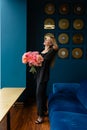 Blonde business lady with content expression holds flowers