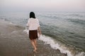 Carefree woman walking barefoot in cold sea waves on sandy beach, enjoying calm evening. Mindfulness Royalty Free Stock Photo