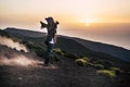 Carefree woman in warm clothing with her arms outstretched on mountain slope admiring scenic view of sunset. Female hiker Royalty Free Stock Photo