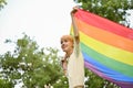 A carefree young Asian gay man with an LGBT flag, feeling freedom and proud, joining LGBTQ+ parade