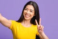 Carefree young asian woman taking selfie and showing peace gesture Royalty Free Stock Photo