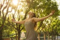 Carefree young attractive woman with her arms raised feeling free while listening music in the park Royalty Free Stock Photo