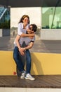 Carefree young couple has fun: girlfriend piggybacking boyfriend. Lovers girl and guy skateboarders
