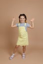 Carefree young female kid with yellow kanekalon pigtails, showing hands five signs looking at camera playing smiling