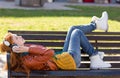 Carefree young lady lying on bench and listening to music