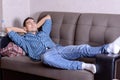 Carefree young man relaxed on the couch with his hands behind his head, dreaming of the future Royalty Free Stock Photo