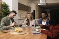 Carefree young people eating and drinking on a modern apartment. Diverse group of relaxed friends having party diner at Royalty Free Stock Photo