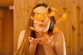 Carefree young woman blowing petals in sauna. Royalty Free Stock Photo