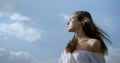 Carefree young woman is flirting with camera, portrait against blue cloudy sky Royalty Free Stock Photo